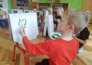 Chłopiec maluje uśmiechniętego kotka